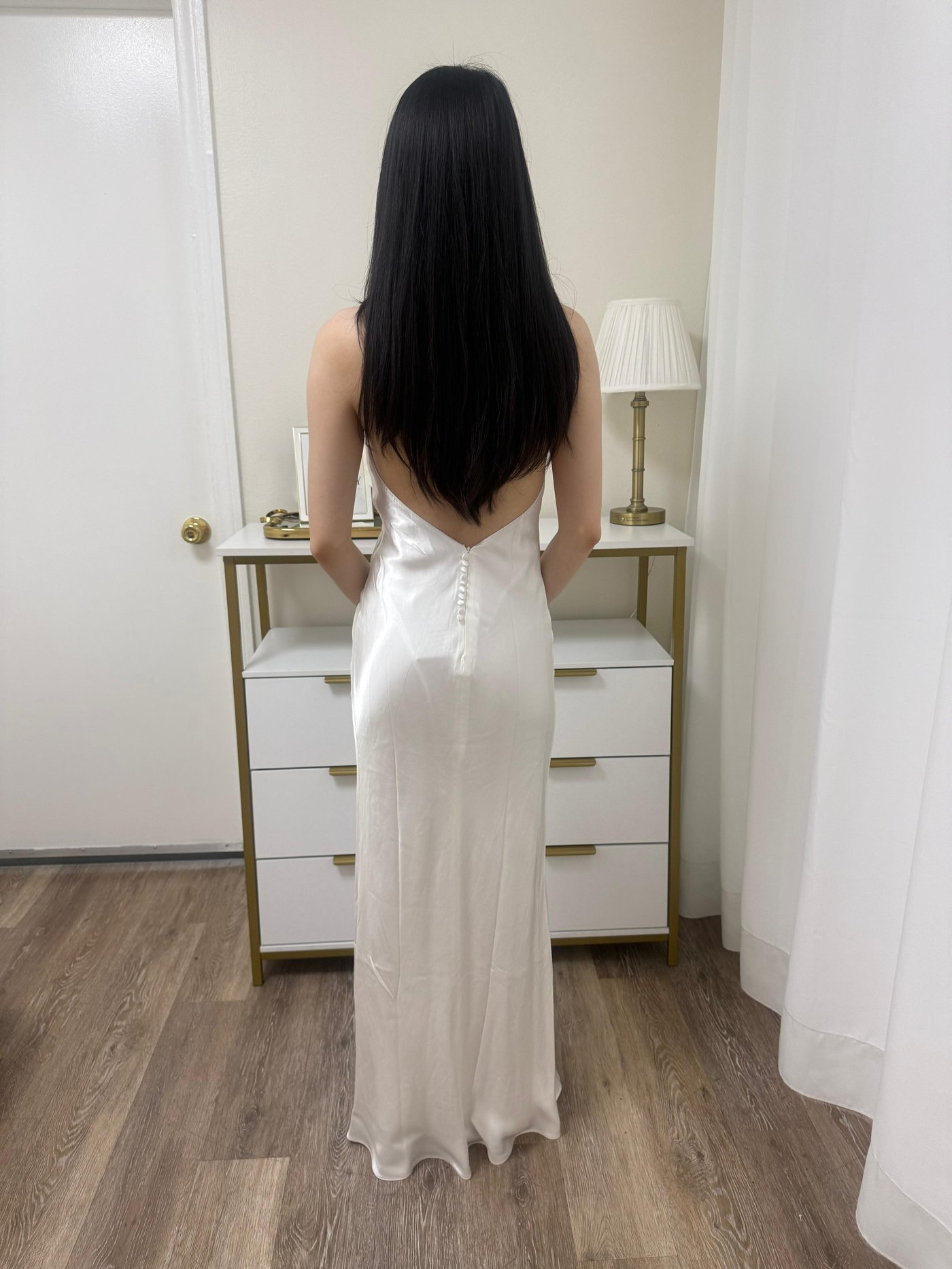 Back view of a white satin slip wedding gown with delicate button detailing after alteration